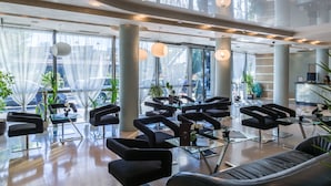 A spacious lobby with modern black chairs, glass tables, and large windows offering a view of the street.