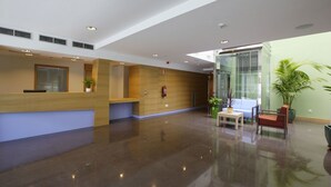 A modern reception area with a wooden reception desk, a seating area with a table and chairs, and potted plants. - Aginaga Hotela (Usurbil)
