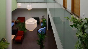 A spacious indoor area with a high ceiling, modern furniture, and hanging lights. - Aginaga Hotela (Usurbil)