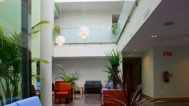 A modern lobby with a glass ceiling, seating areas, and indoor plants. - Aginaga Hotela (Usurbil)