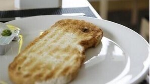 A plate with toasted bread and a small container of butter on a table with two bottles of olive oil in the background. - Aginaga Hotela (Usurbil)