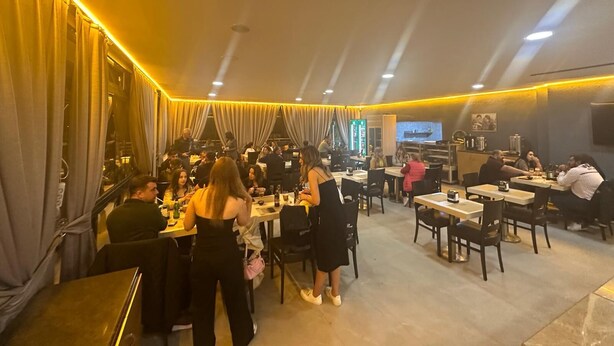 A restaurant with multiple tables and chairs, dim lighting, and a television screen on the wall. - Edirne Park Hotel (Edirne)