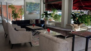A modern interior with a sofa, armchairs, and a coffee table. There are plants and a large window with a view. - Edirne Park Hotel (Edirne)