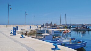 Een jachthaven met aangemeerde boten, een heldere lucht en een verhard pad.