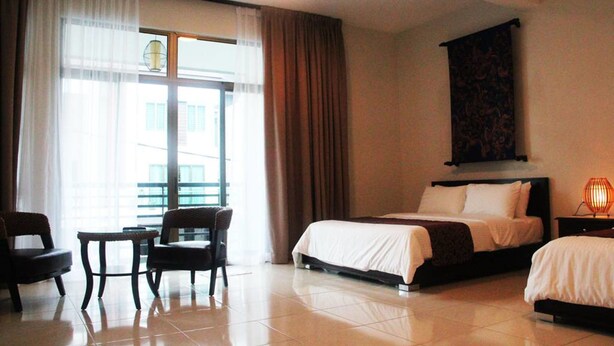 A hotel room with a bed, two chairs, a small table, and a large window with curtains. - Balinese House (Malacca City)
