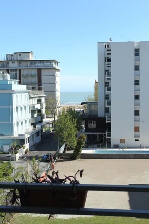 A modern building with multiple floors and balconies, overlooking a coastal area with a clear view of the sea. - Mini Hotel (Rimini)