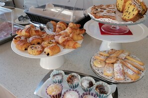 A buffet with various pastries and desserts, including croissants, muffins, and a cake on a stand. - Mini Hotel (Rimini)