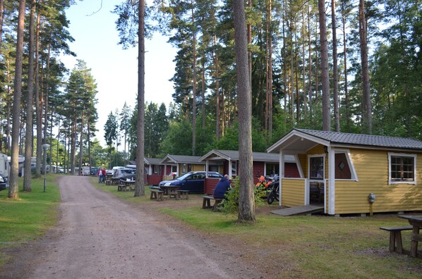 Un camping con varias cabañas, mesas de picnic y un camino de tierra.