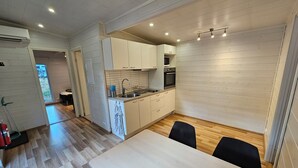A modern kitchen with white cabinets, a sink, and a dining area with a table and chairs.