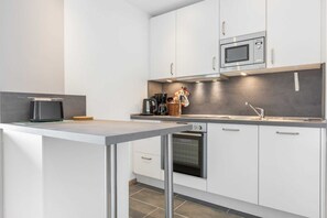 A modern kitchen with white cabinets, a microwave, a toaster, and a sink.