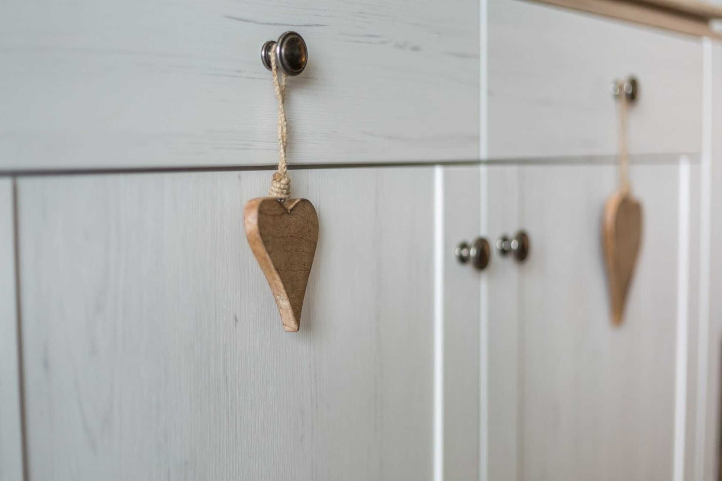 A white wooden door with a heart-shaped decoration hanging from a hook.