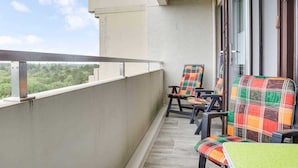 A balcony with two chairs, a view of greenery, and a building exterior. - Apartment 93 (ID 082), Germany (Sankt Peter-Ording)