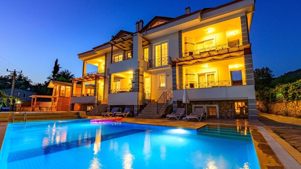 A two-story house with a swimming pool, outdoor seating, and a well-lit interior. - Anatolian Apartments (Fethiye)