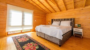 A wooden cabin bedroom with a bed, nightstand, and a large window. - Anatolian Apartments (Fethiye)