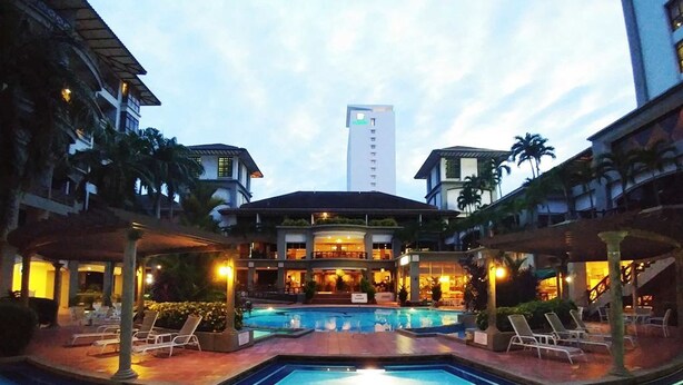 A hotel pool area with lounge chairs, a central pool, and a building with multiple floors and balconies in the background. - Urban Industrial City View (Malacca City)
