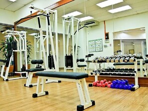 Un gimnasio con equipo de ejercicio variado, incluyendo bancos, mancuernas y máquinas de pesas.