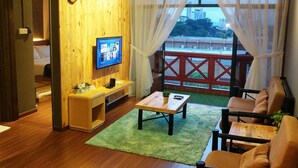 A living room with a wooden wall, a television, a small table, and a sofa. - Urban Industrial City View (Malacca City)