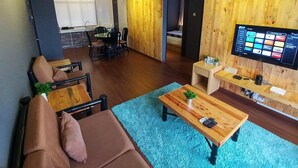 A modern living room with a wooden accent wall, a flat-screen TV, a coffee table, and a sofa. - Urban Industrial City View (Malacca City)