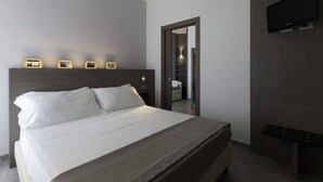 Un dormitorio moderno con una cama grande, un televisor de pantalla plana en la pared y una puerta que da a un baño.