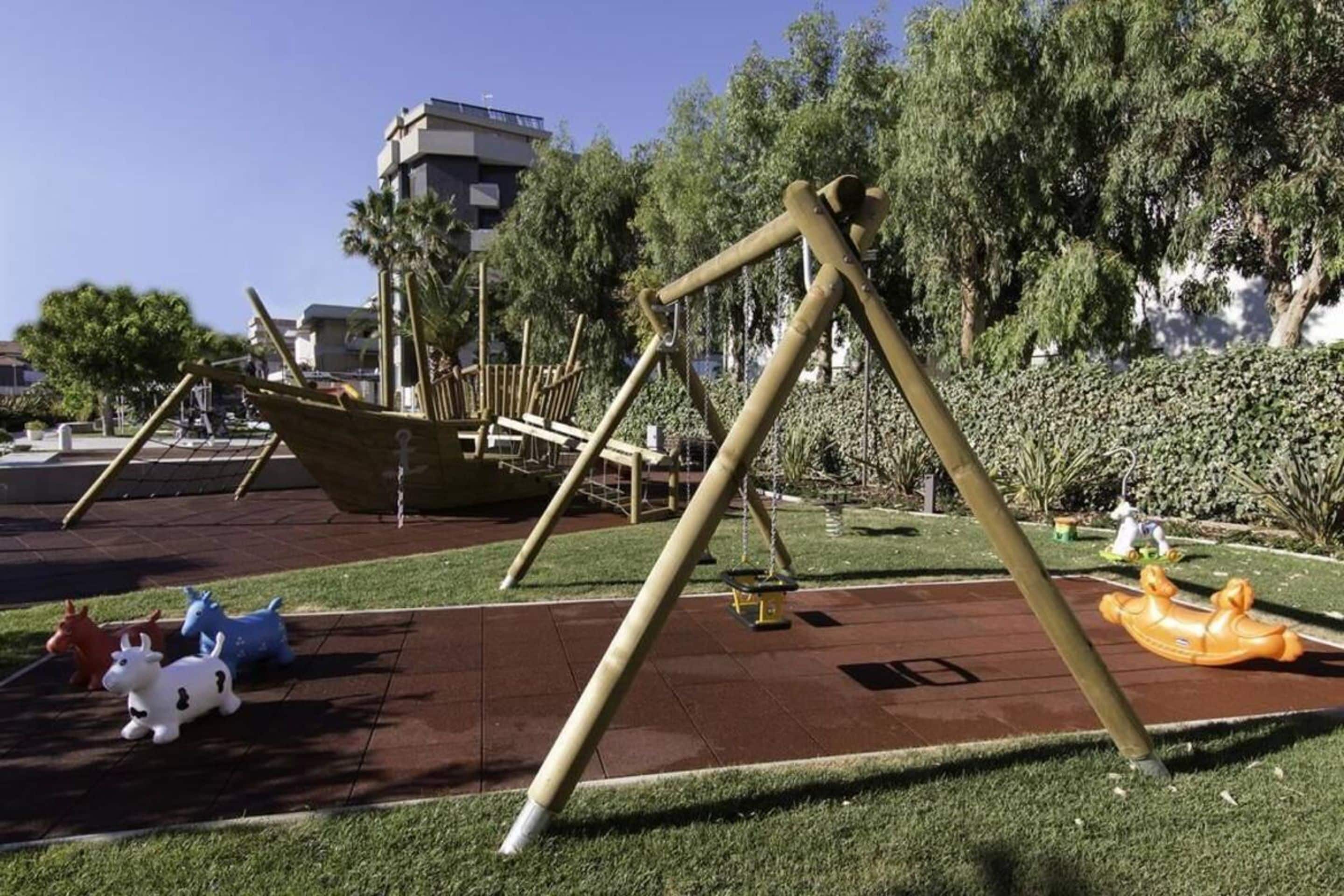 Un'area giochi con altalene, una giostra e un'attrezzatura a forma di barca.