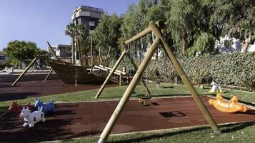 Un'area giochi con altalene, una giostra e un'attrezzatura a forma di barca.