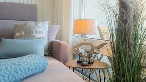 A cozy living room with a sofa, pillows, a lamp, and a tall plant. - Apartment 254 Little time-out (ID 139) (Sankt Peter-Ording)