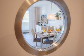 Un coin repas agrémenté d’un grand miroir rond qui reflète la cuisine et l’espace dédié à la salle à manger.
