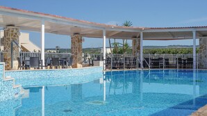 A swimming pool with a tiled edge, surrounded by outdoor seating and a covered area with a red-tiled roof. - 2 bedroom stunning apartment in Grottaglie (TA) (Grottaglie (TA))