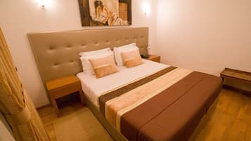 A neatly arranged bedroom with a large bed, a bedside table, a nightstand, and a painting on the wall.