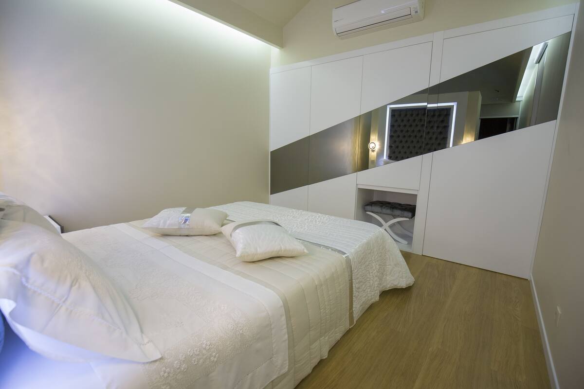 Un dormitorio con cama, armario y espejo.