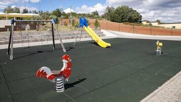 A playground with a slide, swings, and a red and white toy horse.