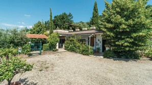 A house with a gravel driveway, surrounded by trees and greenery. - 2 bedroom pet friendly apartment in Magione -PG- (Magione -PG-)