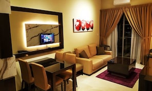 A modern living room with a sofa, chairs, a coffee table, a TV, and artwork. - La Tulipe Sea View (Malacca City)