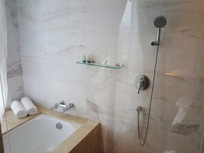Ein Badezimmer mit einer Badewanne, einer Dusche und einem Glastischchen mit Pflegeprodukten.