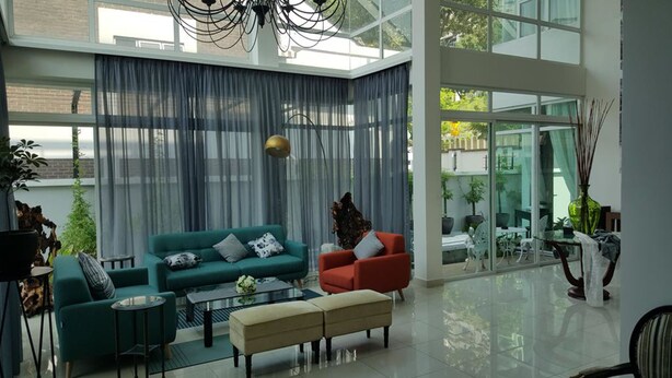 A spacious living room with a large window, a green sofa, a red armchair, and a beige ottoman. - La Maison 100 (Kuala Lumpur)