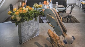 Un comedor con una mesa lista para dos personas, un jarrón de flores y un diseño de silla original.