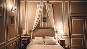 Quarto com uma cama de dossel, um tapete decorativo e uma mesa de cabeceira com abajur.
