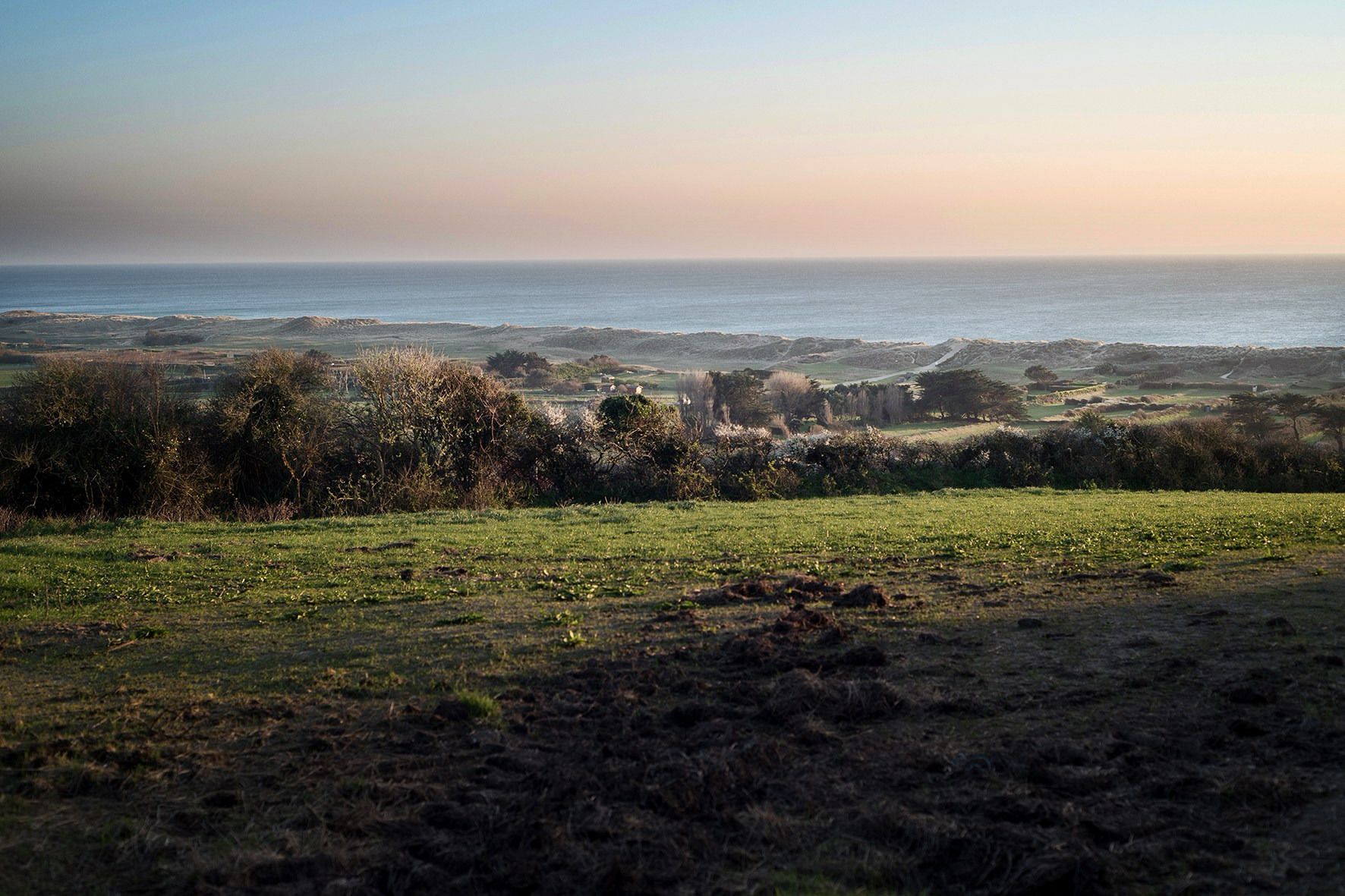 Un paisaje costero con colinas onduladas y vista al mar.