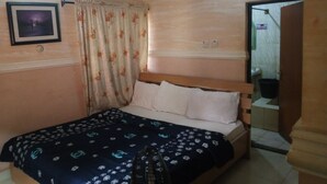 Ein Schlafzimmer mit einem Bett, einem Deckenventilator, einem gerahmten Bild an der Wand und einem Vorhang.