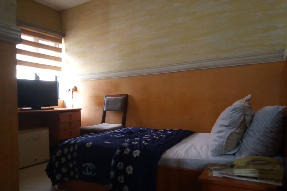 A bedroom with a bed, a chair, a desk, and a television.