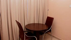 Ein Zimmer mit einem runden Holztisch und zwei roten Stühlen.
