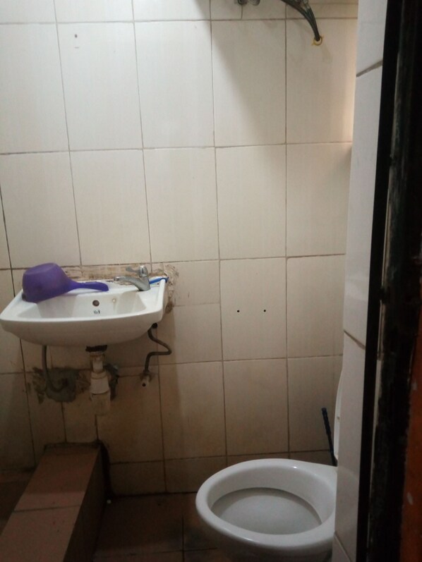 A small bathroom with a white sink, a purple toothbrush holder, and a white toilet. - Maitama Guest House (Abuja)