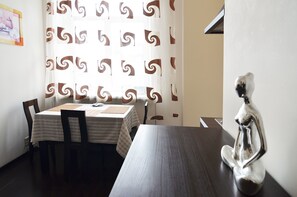 A dining area with two tables, chairs, a decorative silver statue, and a patterned curtain. - Rent Kiev Lva Tolshtoho Square (Kyiv)