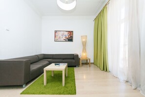 A modern living room with a grey sectional sofa, a small wooden coffee table, a green rug, a floor lamp, and a painting on the wall. - Rent Kiev Lva Tolshtoho Square (Kyiv)