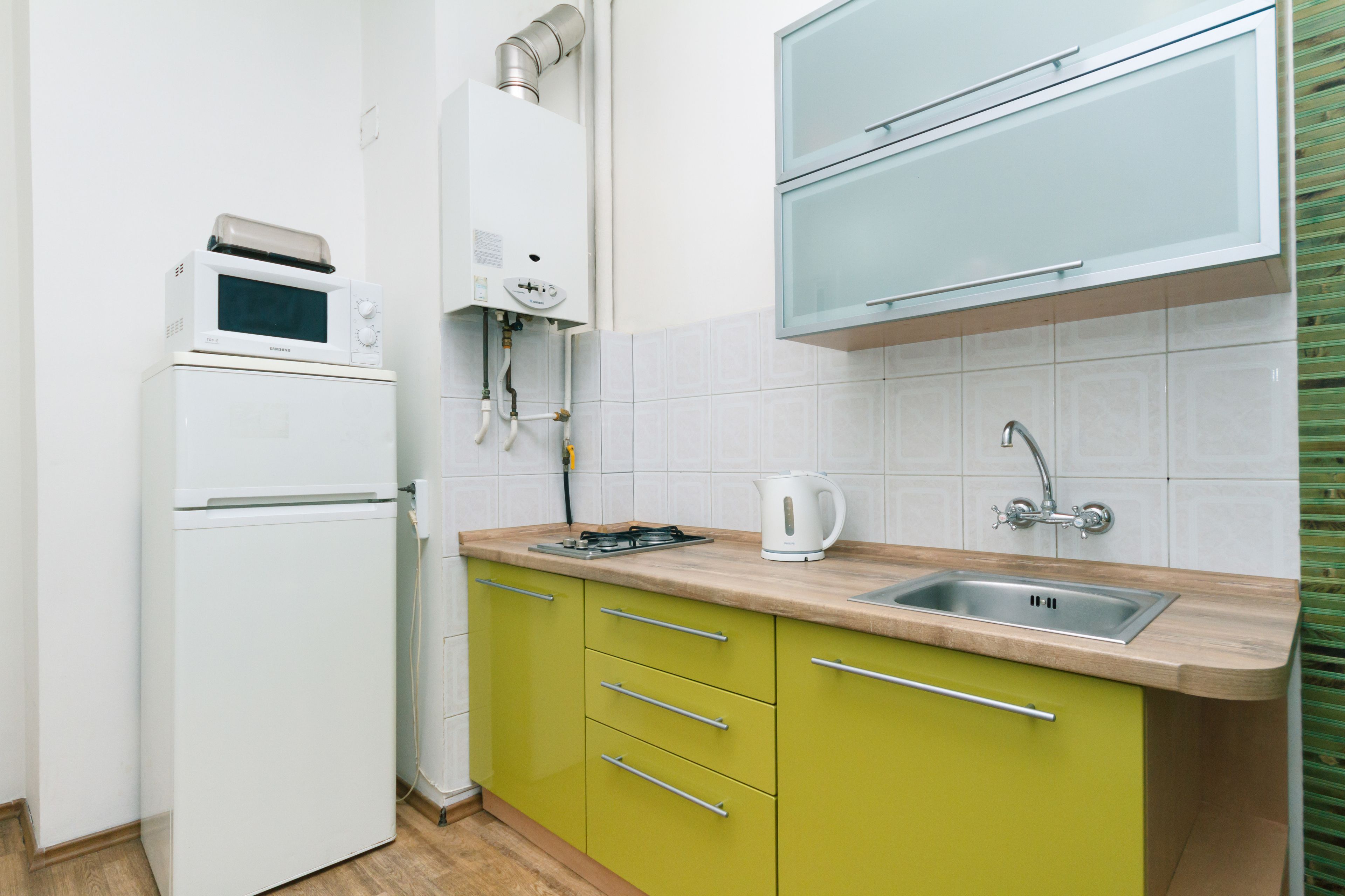 A compact kitchen with a refrigerator, microwave, stove, sink, and cabinets.