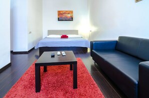 A modern hotel room with a bed, a red rug, a black leather sofa, and a painting on the wall. - Rent Kiev Lva Tolshtoho Square (Kyiv)