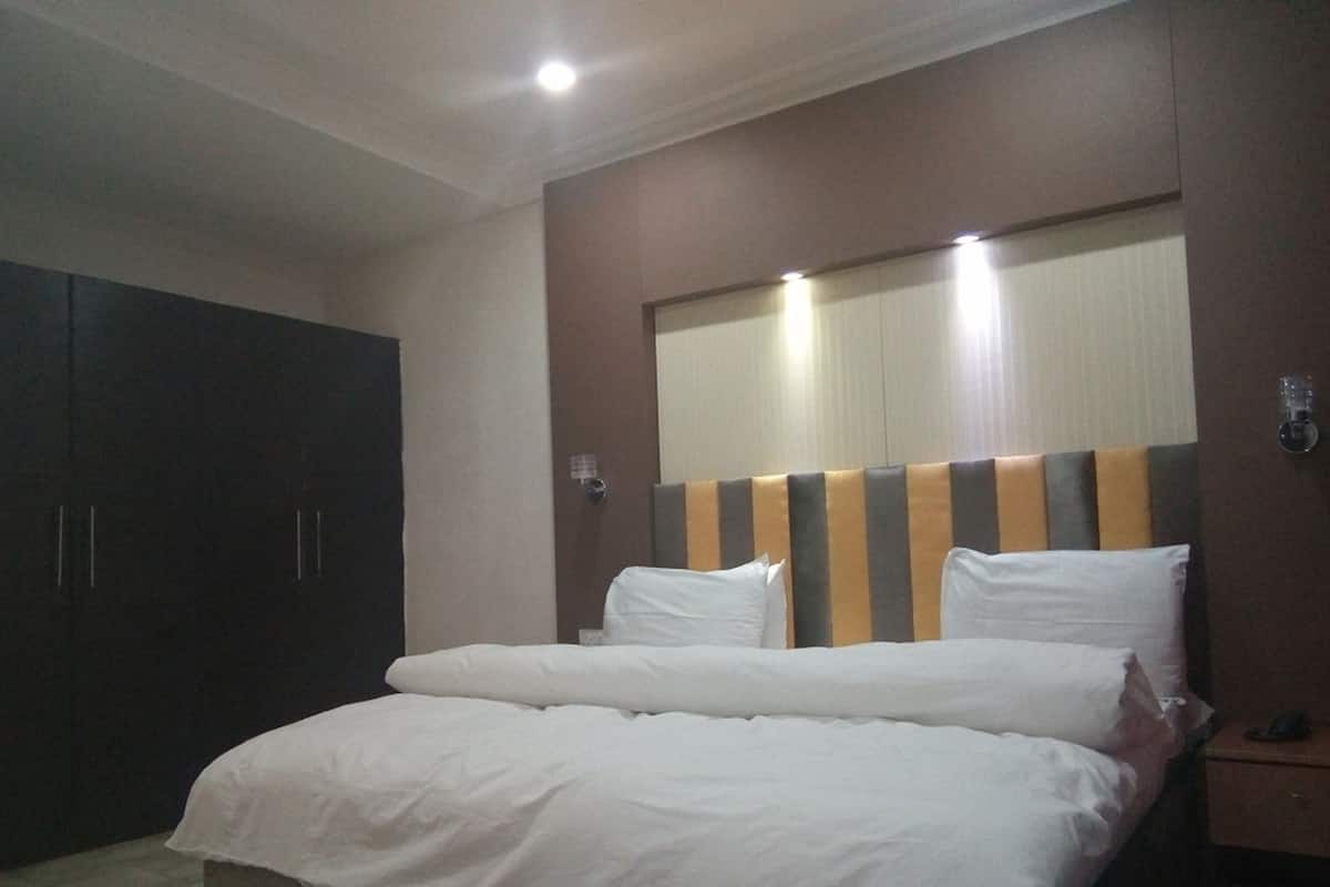Ein Hotelzimmer mit einem großen Bett, einem Kleiderschrank und einem Nachttisch mit Lampe.