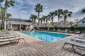 A pool area with lounge chairs and a covered seating area.