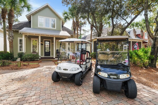A golf cart parked in front of a house with a porch and a mailbox.