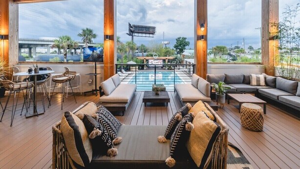Un espace de détente extérieur avec une piscine, des coins salon et une vue sur le paysage urbain.